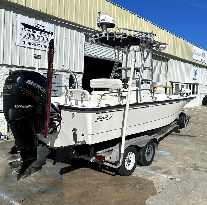 Slide: The Image of 2015 Boston Whaler 210 Montauk boat on trailer, parked outside a warehouse. - 2