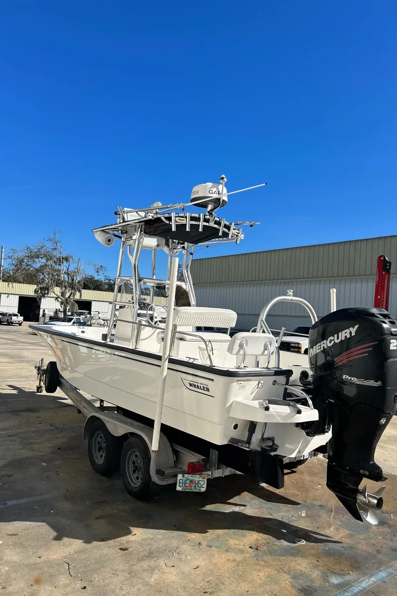 Slide: The Image of 2015 Boston Whaler 210 Montauk boat with Mercury engine on trailer, under clear blue sky. - 5
