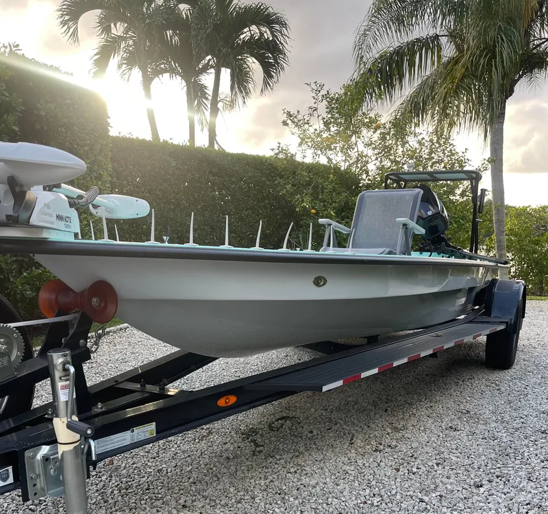 Slide: The Image of 2024 Cayo Boatworks 173 on trailer, surrounded by palm trees at sunset. - 21