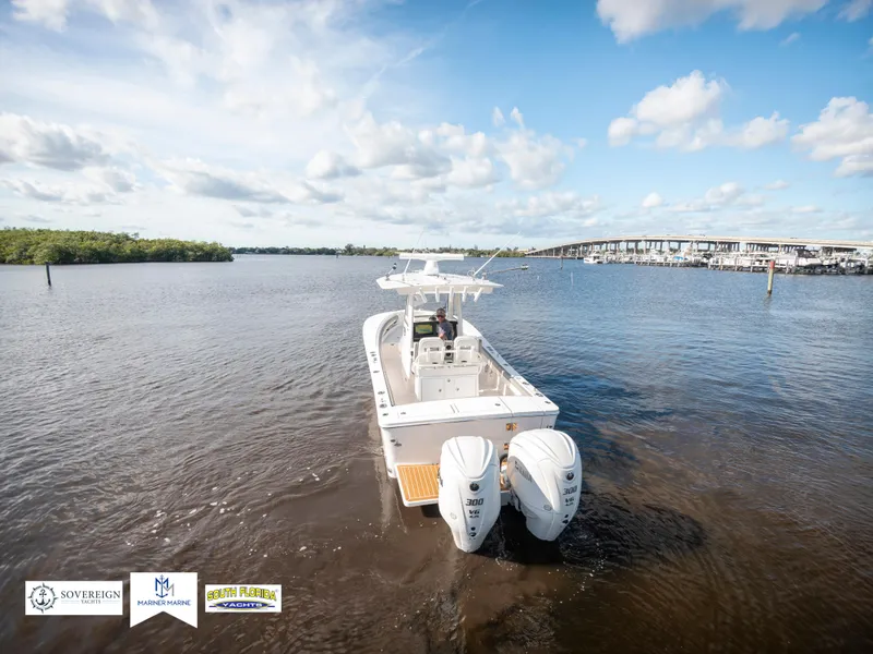 Slide: The Image of 2024 Regulator 28 boat on calm water with twin engines, under a partly cloudy sky. - 13