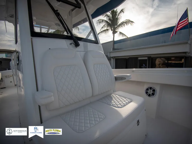 Slide: The Image of 2024 Regulator 31 boat interior with white cushioned seats, palm tree, and American flag in background. - 21
