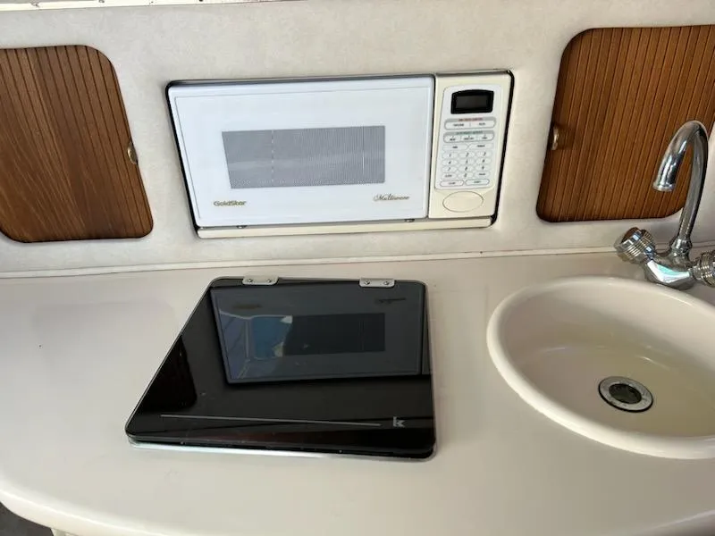 Slide: The Image of 1997 Sea Ray Sundancer galley with microwave, sink, and closed laptop. - 6