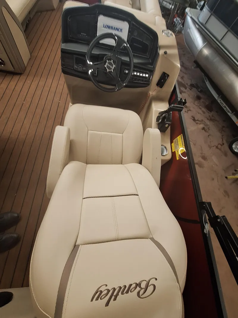 Slide: The Image of 2024 Bentley Pontoons Elite 253 SwingBack DC interior with captain's chair and steering console. - 7