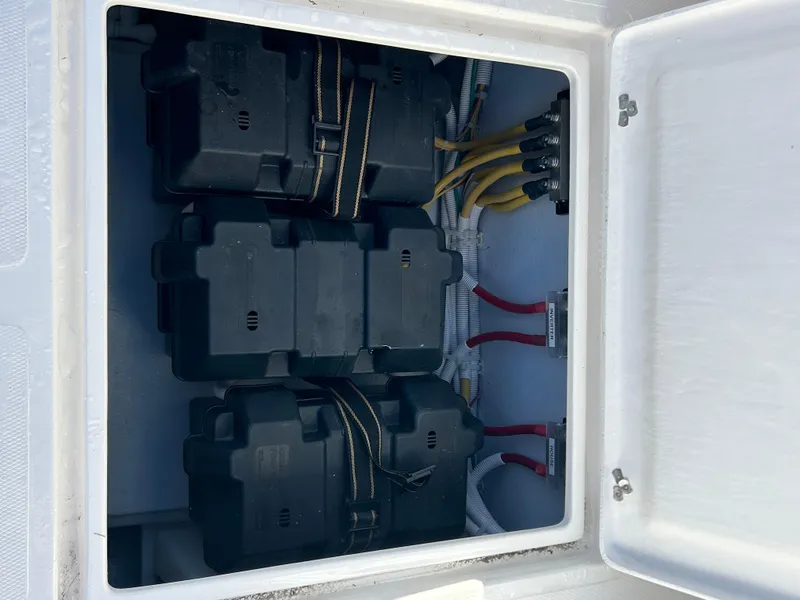 Slide: The Image of 2024 NorthCoast 315HT boat battery compartment with secured black battery boxes and wiring. - 15