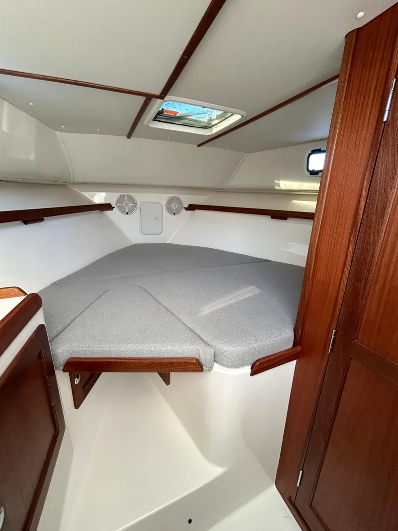 Slide: The Image of 2024 NorthCoast 315HT cabin interior with wood accents and cushioned berth. - 26