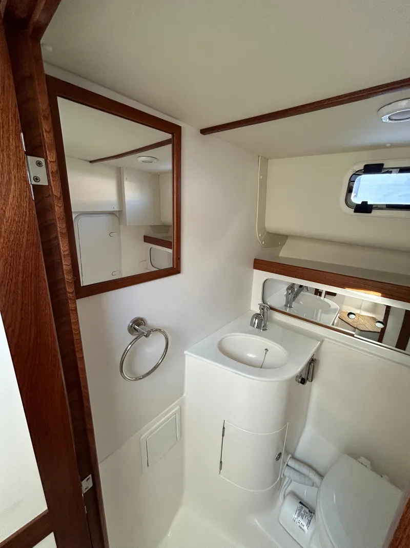 Slide: The Image of 2024 NorthCoast 315HT boat bathroom with sink, mirror, and toilet. - 27