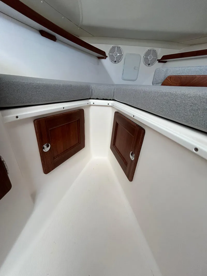 Slide: The Image of 2024 NorthCoast 315HT cabin interior with wooden storage panels and cushioned seating. - 28