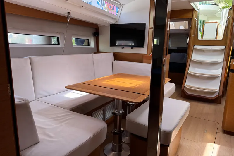 Slide: The Image of Interior of 2018 Jeanneau Sun Odyssey 440 yacht with white seating and wooden table. - 20