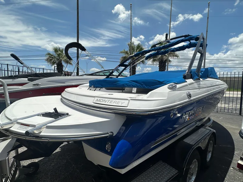 Slide: The Image of 2024 Monterey 224 FS boat with blue cover on trailer, parked outdoors. - 4