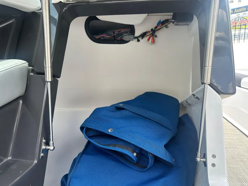Slide: The Image of 2024 Monterey 224 FS boat storage compartment with blue cover and wiring. - 40