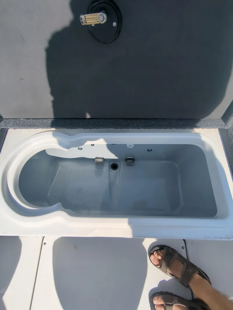 Slide: The Image of 2024 Triton 186 Allure boat livewell with open lid and foot visible. - 9