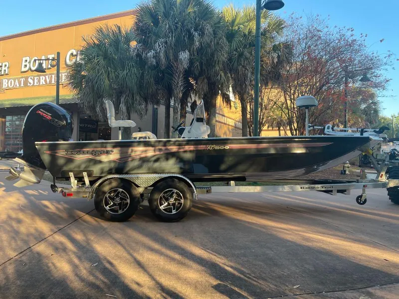 The Image of 2024 Ranger RB200 boat on trailer, parked near palm trees and a boat service center. - 0