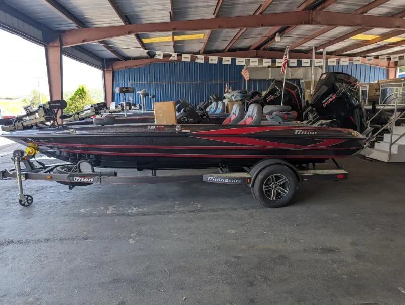 The Image of 2024 Triton 18 TrX bass boat on trailer in a covered storage area. - 0
