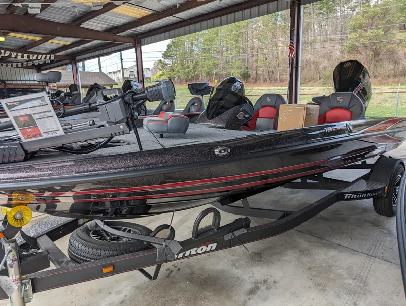 Slide: The Image of 2024 Triton 18 TrX bass boat in showroom, featuring sleek black and red design. - 3