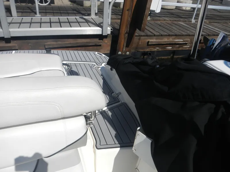 Slide: The Image of 2009 Larson 238 LXi boat interior with white seats and dock in background. - 8