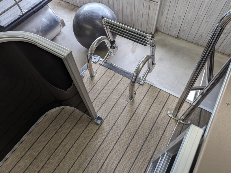 Slide: The Image of 2024 Sylvan Mirage Fish 8522 Party Fish boat deck with ladder and striped flooring. - 8