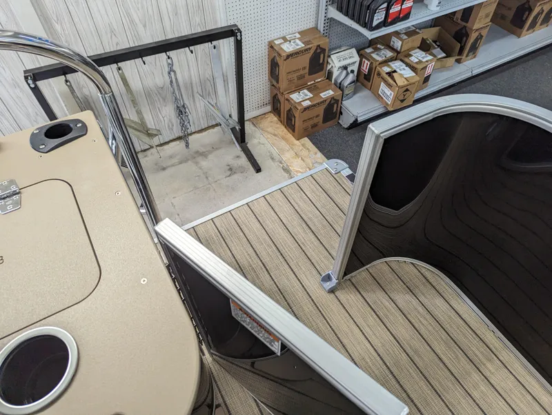 Slide: The Image of 2024 Sylvan Mirage Fish 8522 Party Fish boat interior with beige flooring and storage boxes. - 9