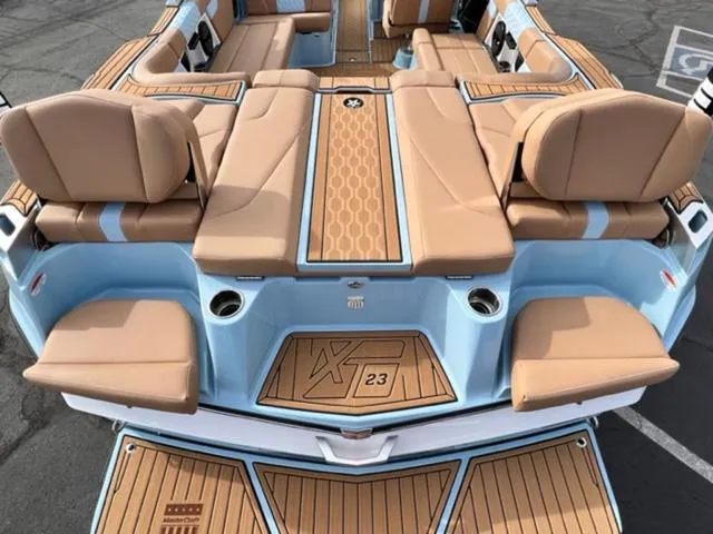 Slide: The Image of 2024 MasterCraft XT23 boat on trailer, light blue and white, parked outdoors. - 10