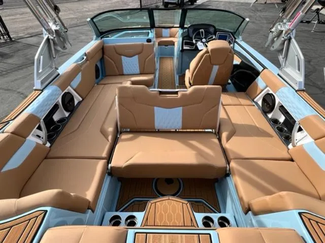 Slide: The Image of 2024 MasterCraft XT23 boat on trailer, light blue and white design, parked outdoors. - 12