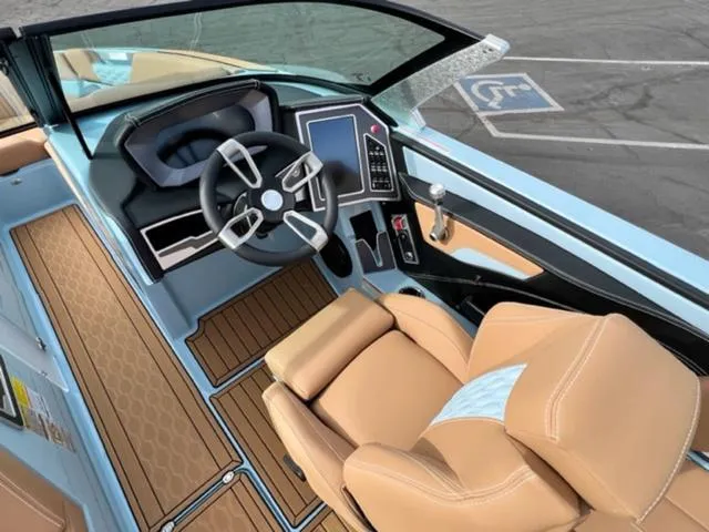 Slide: The Image of 2024 MasterCraft XT23 boat on trailer, light blue and white design, parked outdoors. - 13