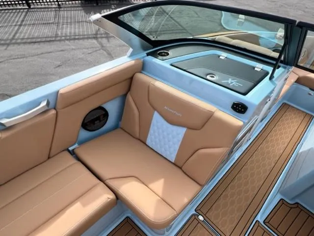 Slide: The Image of 2024 MasterCraft XT23 boat on trailer, light blue exterior, parked outdoors. - 14