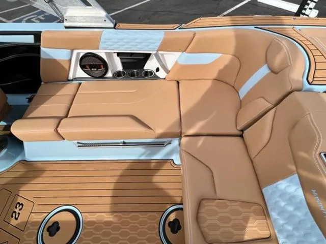 Slide: The Image of 2024 MasterCraft XT23 boat with tan and blue seating, rear view. - 17