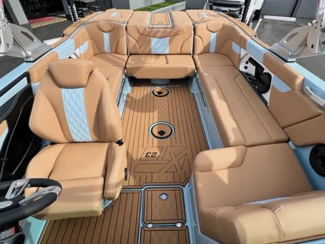 Slide: The Image of 2024 MasterCraft XT23 boat interior with tan seating and modern dashboard. - 19