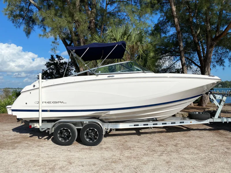 The Image of 2017 Regal 22 FasDeck boat on a trailer, parked outdoors near trees. - 0