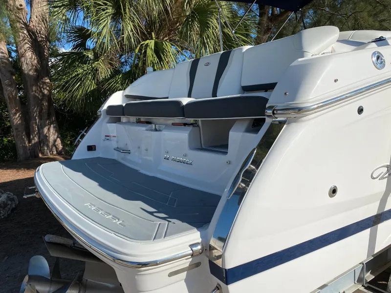 Slide: The Image of 2017 Regal 22 FasDeck boat with swim platform and seating, docked near palm trees. - 4