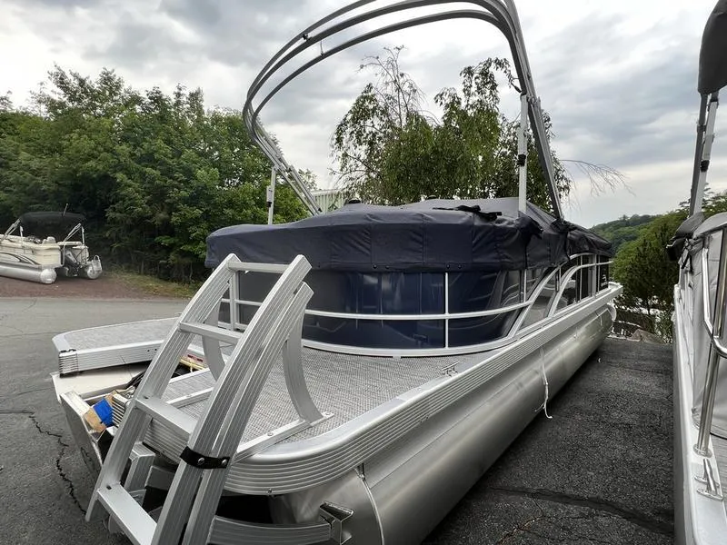 Slide: The Image of 2024 Bennington 22 SXSR pontoon boat with canopy and ladder, parked on asphalt. - 2