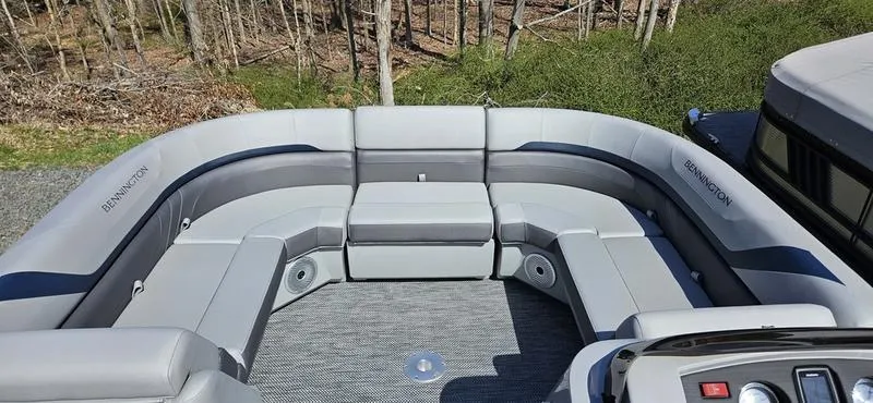 Slide: The Image of 2024 Bennington 22 SXSR pontoon boat with spacious seating, set in a wooded area. - 8