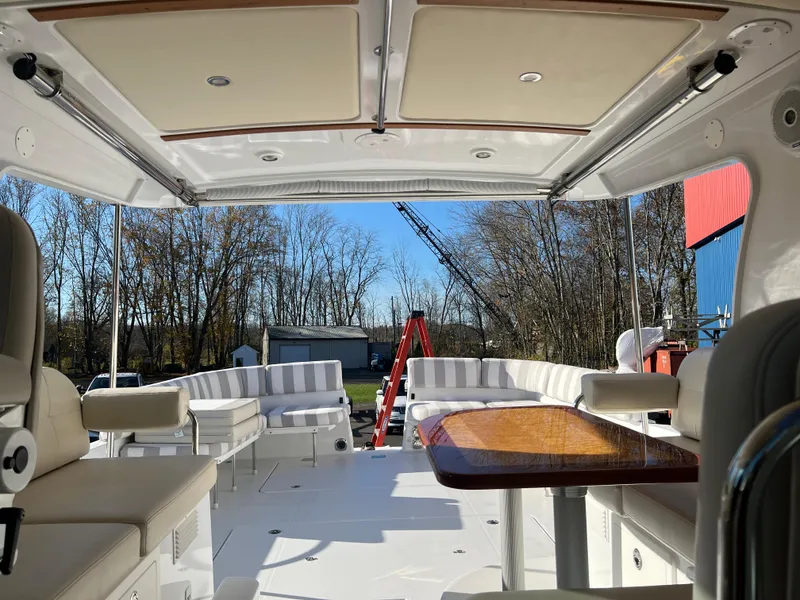 Slide: The Image of 2017 Back Cove Downeast 37 boat interior with seating and table, docked outdoors. - 40