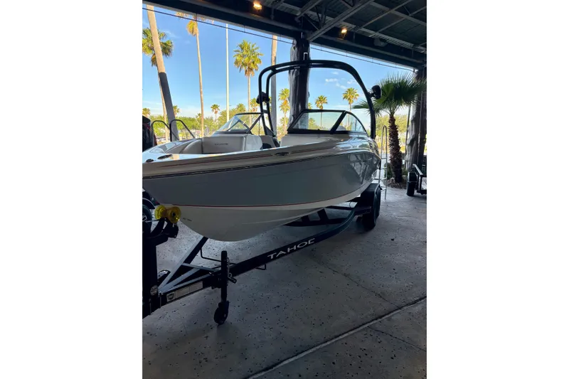 Slide: The Image of 2024 Tahoe 210 S boat on trailer in showroom with palm trees outside. - 10