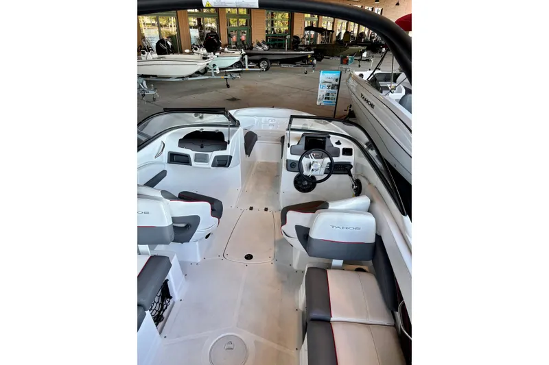 Slide: The Image of 2024 Tahoe 210 S boat interior with seating and steering wheel in showroom. - 13