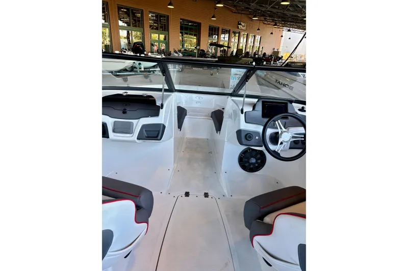 Slide: The Image of 2024 Tahoe 210 S boat interior with modern dashboard and seating in showroom. - 8