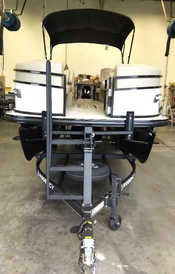 Slide: The Image of 2024 Regency 230 DL3 pontoon boat on a trailer in a warehouse. - 2