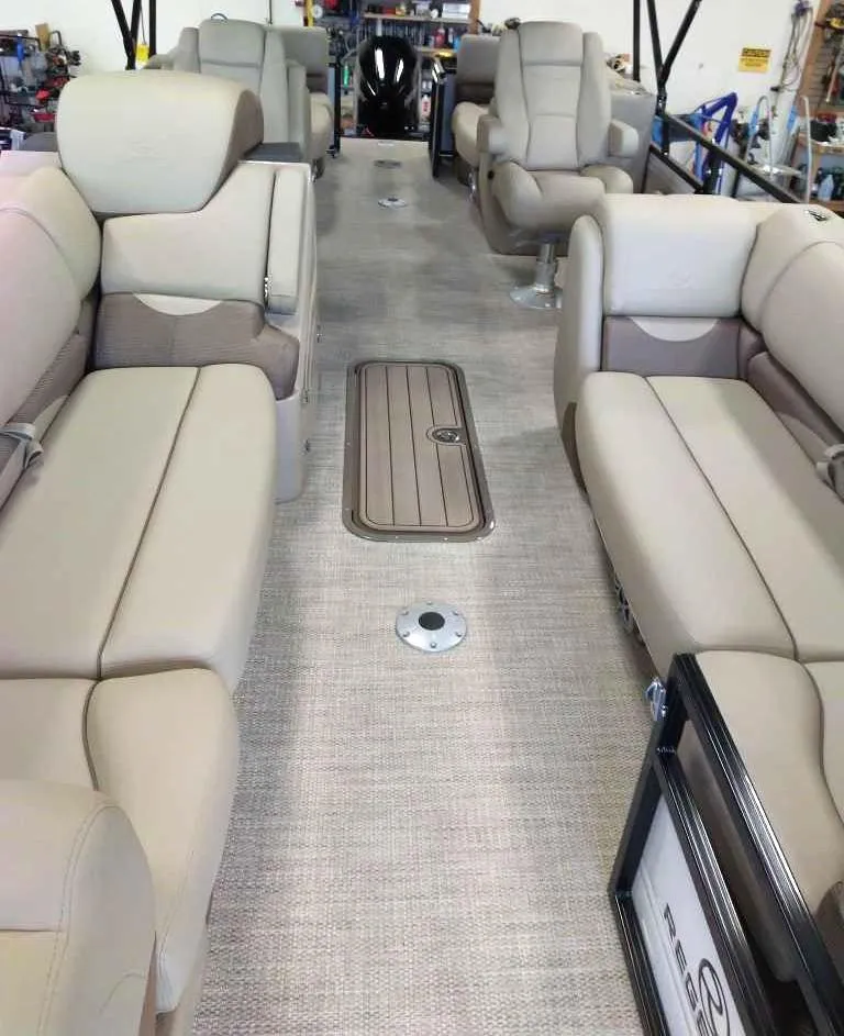 Slide: The Image of 2024 Regency 230 DL3 pontoon boat interior with beige seating and carpet. - 5