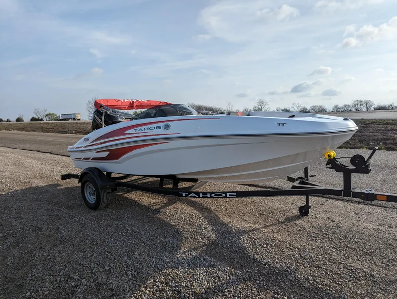 Slide: The Image of 2024 Tahoe T16 boat on trailer with red accents, parked on gravel. - 9