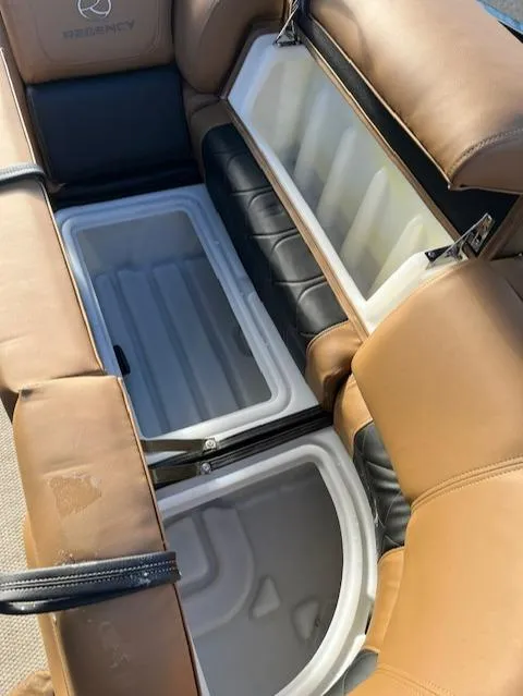 Slide: The Image of 2024 Regency 230 LE3 boat with open storage compartments and tan leather seats. - 12