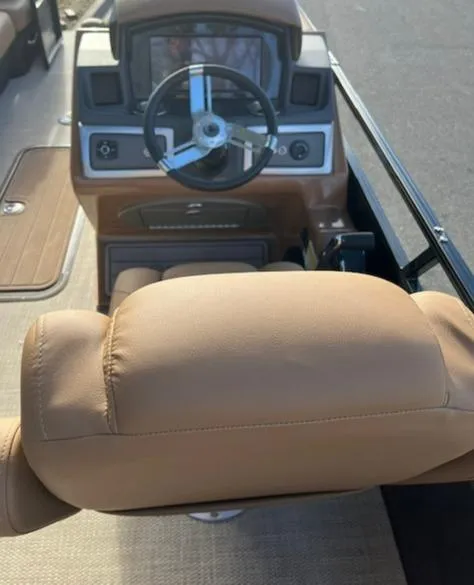 Slide: The Image of 2024 Regency 230 LE3 boat helm with tan captain's chair and modern dashboard. - 15