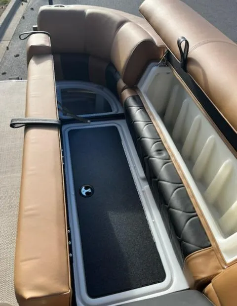 Slide: The Image of 2024 Regency 230 LE3 boat with open storage compartment and tan leather seats. - 17