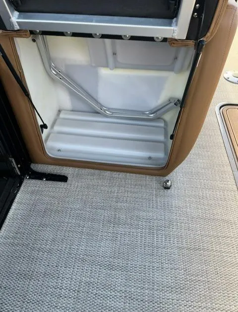 Slide: The Image of 2024 Regency 230 LE3 boat interior storage compartment with beige and white finish. - 21