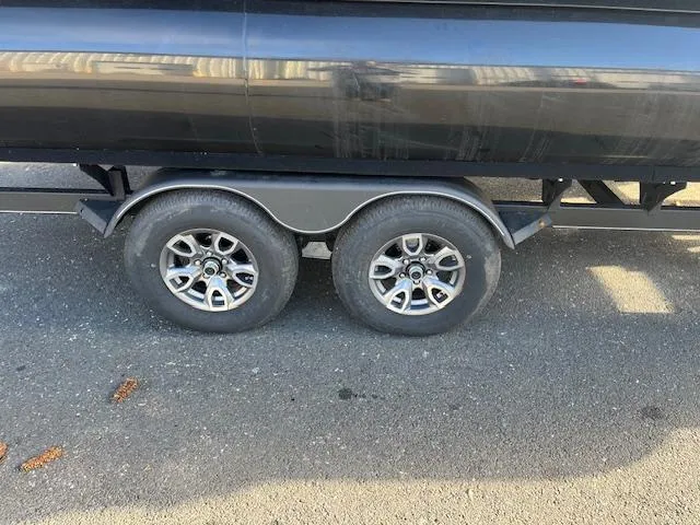 Slide: The Image of 2024 Regency 230 LE3 trailer with dual axle wheels on asphalt. - 27