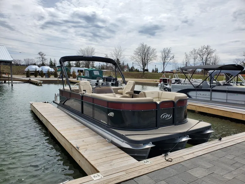 Slide: The Image of 2022 Manitou Aurora LE VP pontoon boat docked at a marina. - 2