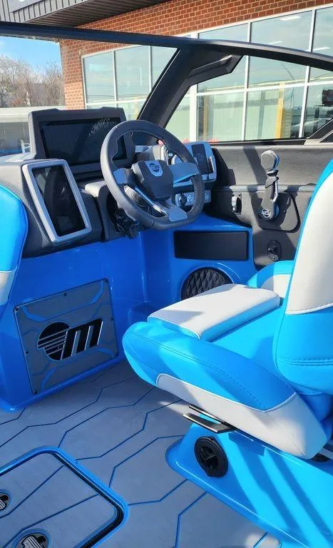 Slide: The Image of 2024 Malibu 23 MXZ boat interior with blue and white seats, modern dashboard, and steering wheel. - 12