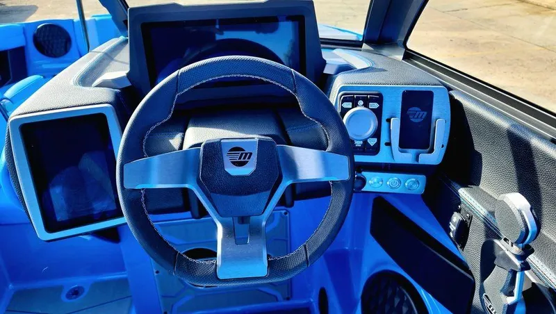 Slide: The Image of 2024 Malibu 23 MXZ boat dashboard with steering wheel and control panel. - 16