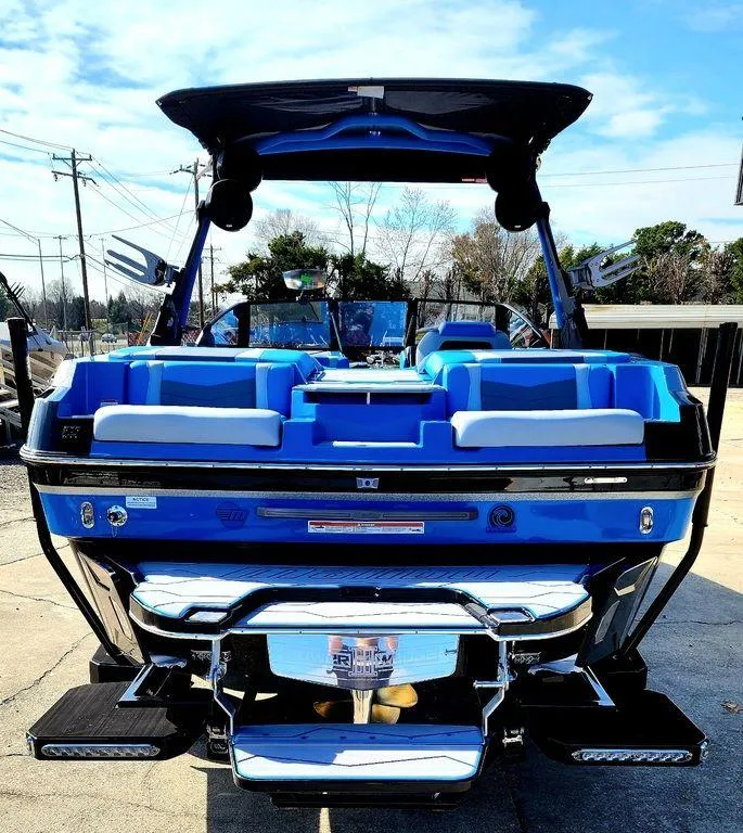 Slide: The Image of 2024 Malibu 23 MXZ boat, rear view, blue and white interior, docked. - 8