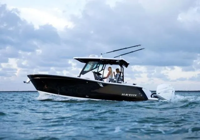 Slide: The Image of 2024 Blackfin 272CC boat cruising on open water under cloudy skies. - 1