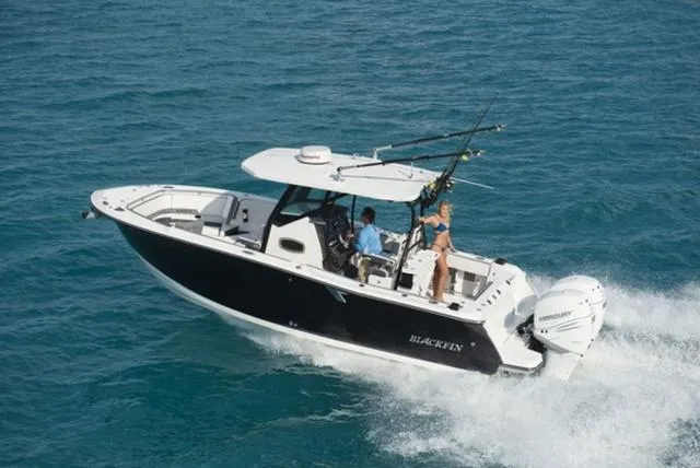 Slide: The Image of 2024 Blackfin 272CC boat cruising on open water, featuring fishing rods and dual engines. - 13