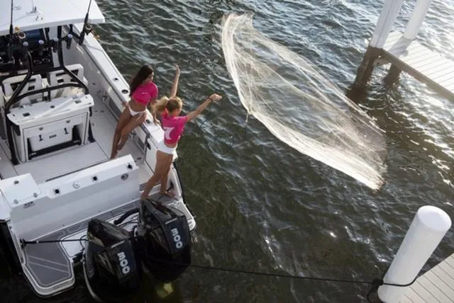 Slide: The Image of Two people casting a fishing net from a 2024 Blackfin 272CC boat. - 15